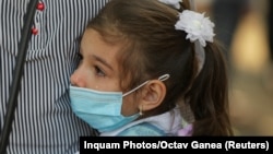 A Romanian schoolchild cries and hugs her mother on the first day of the 2020-21 school year amid the coronavirus pandemic in Bucharest on September 14.