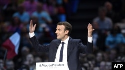 France -- Presidential election candidate for the En Marche ! movement Emmanuel Macron raises his hands on stage as he delivers a speech during a campaign meeting in Paris, April 17, 2017