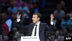 France -- Presidential election candidate for the En Marche ! movement Emmanuel Macron raises his hands on stage as he delivers a speech during a campaign meeting in Paris, April 17, 2017