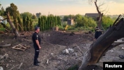 A Ukrainian policeman stands next to a crater caused by a Russian missile in the Kyiv region on August 27. 