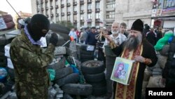 Sveštenik daje blagoslov proruskim separatistima, Donjeck, 24. april 2014.