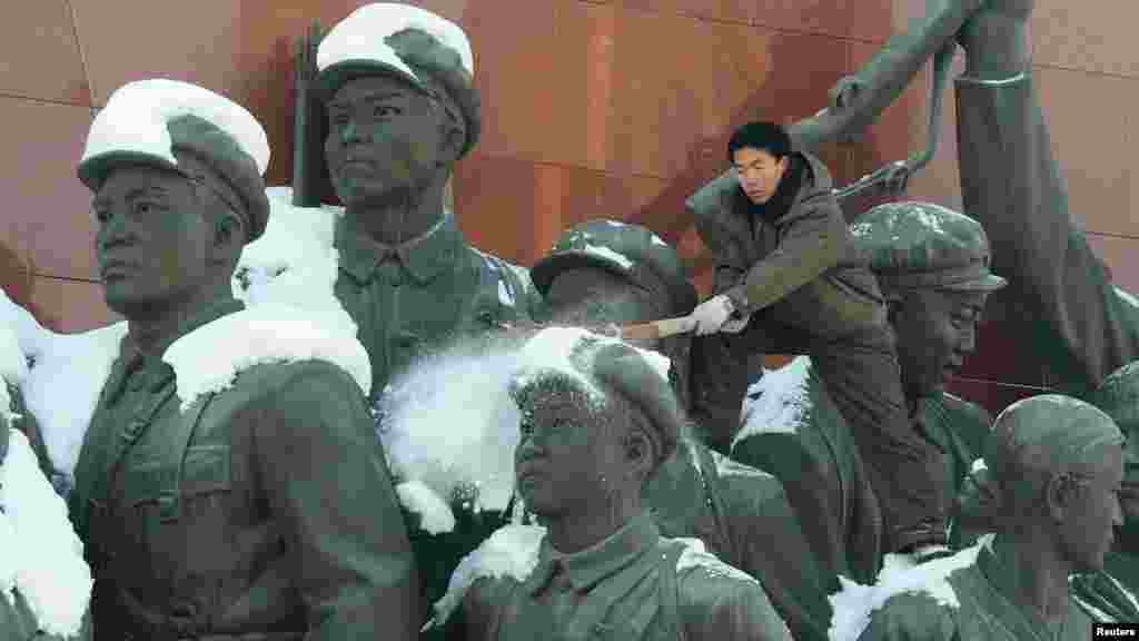 A man brushes snow off the top of a monument in Pyongyang, North Korea. (Reuters/Kyodo)