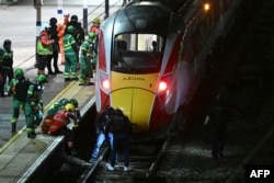 Policajci i pripadnici hitnih službi pretražuju prugu ispod voza LNER Azuma na stanici Huntingdon u Huntingdonu, u istočnoj Engleskoj, 1. novembra 2025. godine, nakon uboda nožem u vozu.