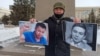 A activist holds up photos of Dulat Agadil (left) and his son Zhanbolat.