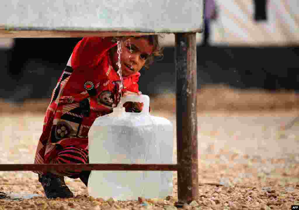 An Iraqi refugee girl, who fled the Iraqi city of Mosul due to the fighting between government forces and Islamic State (IS) militants, fills a container with water at a UN-run refugee camp in Syria's Hasakeh Province. (AFP/Delil Souleiman)
