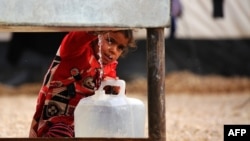 An Iraqi refugee girl who fled the Iraqi city of Mosul due to the fighting between government forces' and Islamic State (IS) militants, fills a container with water at a UN-run refugee camp in Syria's Hasakeh Province.