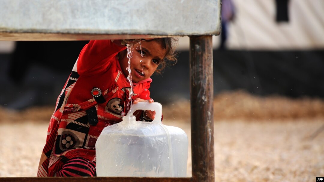 An Iraqi refugee girl who fled the Iraqi city of Mosul due to the fighting between government forces' and Islamic State (IS) militants, fills a container with water at a UN-run refugee camp in Syria's Hasakeh Province.