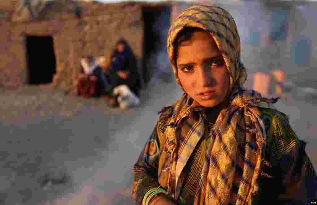 A young girl internally displaced from Afghanistan's Faryab Province poses for a picture near her temporary shelter at a camp on the outskirts of Herat. (epa/Jalil Rezayee)