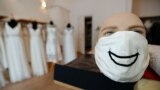 Модельер Фридерике Йорциг надевает маску на манекен в своем магазине в Берлине.