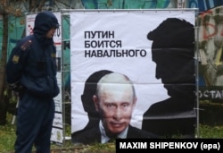 Полицейский возле плаката с изображением Алексея Навального (справа) и президента России Владимира Путина. Киров, 16 октября 2013 года