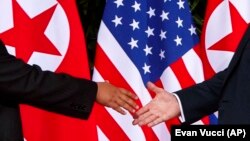 Обмен рукопожатием президента США Дональда Трампа (справа) и лидера Северной Кореи Ким Чен Ына. Сентоса (Сингапур), 12 июня 2018 года.
