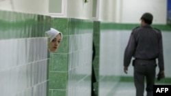 A female inmate peers from behind a wall in the female section of Evin prison. (file photo)