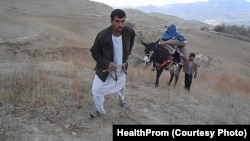 انتقال یک مریض به کلینیک صحی با استفاده از یک الاغ. در بیشتر مناطق دور دست افغانستان مردم به کلینیک های صحی دسترسی ندارند و به نسبت نبود سرک مجبور اند مریضان شان را ذریعۀ حیوانان به مراکز صحی انتقال دهند