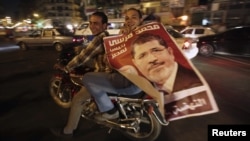 Supporters of Egyptian President Muhammad Morsi hold up his poster as they celebrate while riding a motorbike on Tahrir Square in Cairo on July 9.