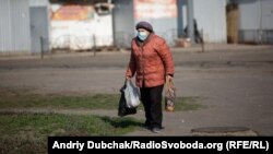 Літня жінка з пакетами продуктів йде з магазину в одному з районів Києва, 7 квітня 2020 року