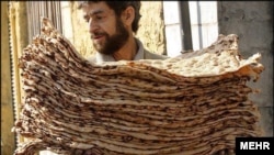 An Iranian man carries a stack of the traditional bread known as sangak.