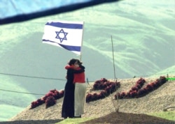 دو دختر نوجوان اسرائیلی در یادبود هفت همکلاسی خود که به ضرب گلوله سرباز اردنی کشته شدند، یکدیگر را در آغوش کشیده‌اند/ دوم مارس ۱۹۹۸