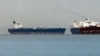 Singapore -- Vessels sail past the Malta-flagged Iranian crude oil supertanker Delvar (L) anchoring off Singapore, 01Mar2012