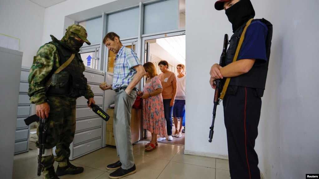 Жители Херсона проходят проверку на входе в здание, где подают заявления на получение российских паспортов, которые теперь требуют в оккупированном регионе для работы, управления автомобилем и получения пособий, 25 июля 2022 года