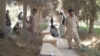 Relatives mourn next to the coffins of policemen who were killed after a Taliban attack on a military outpost in Baghlan Province on August 15.