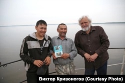 Виктор Кривоногов Енисейде кет халқының өкілдерімен бірге қолына осы этнос туралы жазған кітабын ұстап отыр