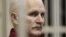 Belarusian human rights activist Ales Byalyatski sits in a guarded cage in a courtroom in Minsk during his trial in November 2011.