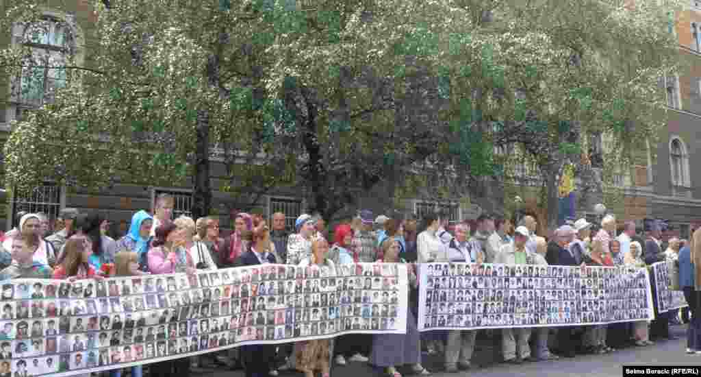 People hold a placard with portraits of people killed in the 1995 Srebrenica massacre.