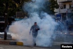 Një protestues kalon përmes gazit lotsjellës të hedhur nga policia në Tiranë më 18 tetor.