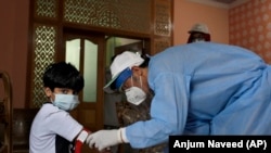 A health worker takes blood sample of a boy during door-to-door testing and screening for the coronavirus in the capital, Islamabad on June 10.