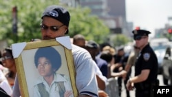 A man holds a portrait of a young Michael Jackson as he and other people wait in line for a public memorial for the late pop icon in New York in June.