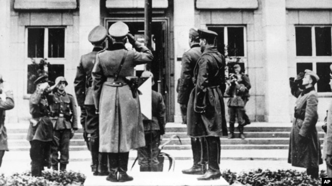 Военнослужащие нацистской Германии и СССР отдают честь немецком флагу со свастикой во время торжеств в рамках военного парада по случаю разделения земель, принадлежавших до этого Польше