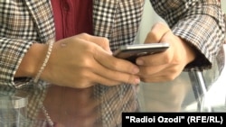 A Tajik young woman checks her mobile phone. (file photo)