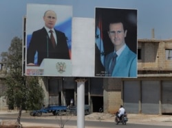 Місцевий житель проїжджає на мотоциклі повз портрети президента Сирії Башара Асада та президента Росії Володимира Путіна в місті Растан, 15 серпня 2018 року