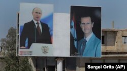 Плакаты с изображением президентов России и Сирии в городе Растан, август, 2018