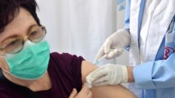 Një grua duke u vaksinuar kundër koronavirusit, në një qendër vaksinimi në Shkup. 31 mars, 2021. 