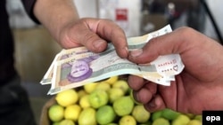 A man pays with 50,000-rial banknotes bearing a portrait of the late revolutionary leader Ayatollah Ruhollah Khomeini to a seller in a shop in Tehran on October 3.