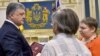 Ukrainian President Petro Poroshenko (left) presents the Hero of Ukraine medal to the parents of Mikhail Zhyzneuski in Kyiv on June 13.