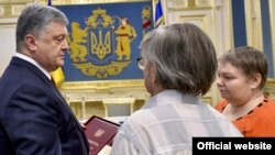 Ukrainian President Petro Poroshenko (left) presents the Hero of Ukraine medal to the parents of Mikhail Zhyzneuski in Kyiv on June 13.