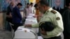 An Iranian police colonel votes in Iranian parliamentary elections that were reportedly marred by low turnout.