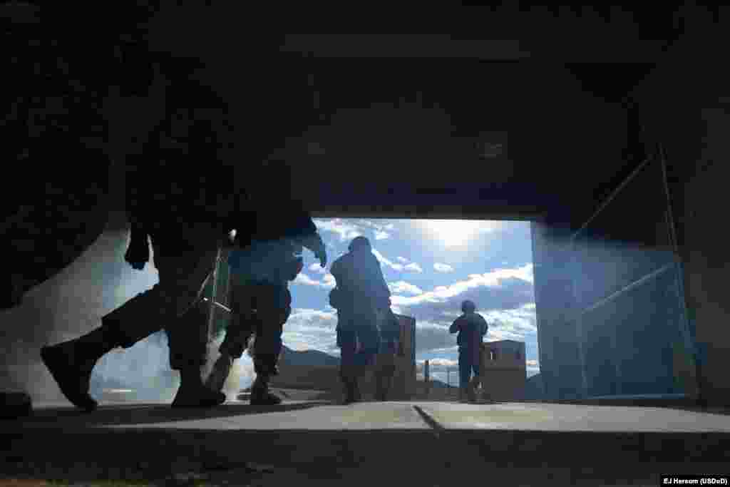 The National Training Center is used to simulate a wide range of situations that the U.S. military may face in combat. Here, soldiers walk through an entryway clouded by smoke.