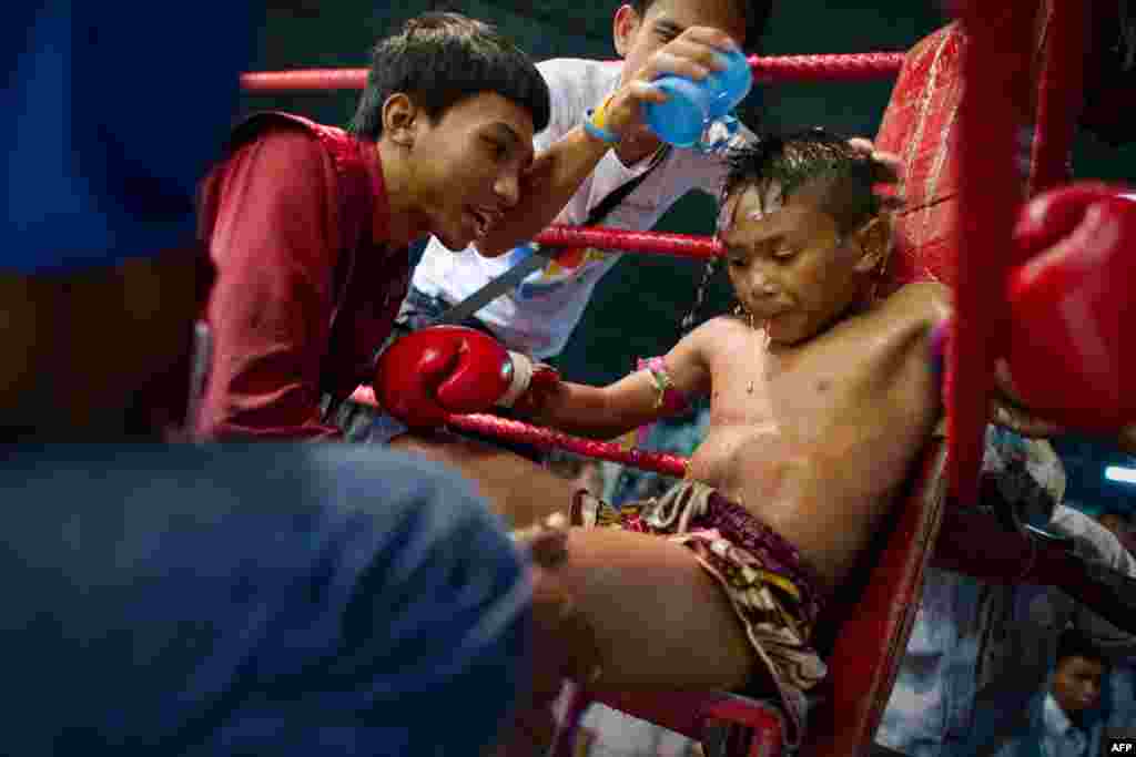 A young Muay Thai boxer resting and getting coached between rounds in his corner 