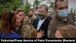 Наразылардың қарсылығына тап болып, бетіне сұйықтық шашылған бұрынғы президент Петро Порошенко жақтастарымен кездесіп жатыр. Тамыз айы, 2021 жыл. 