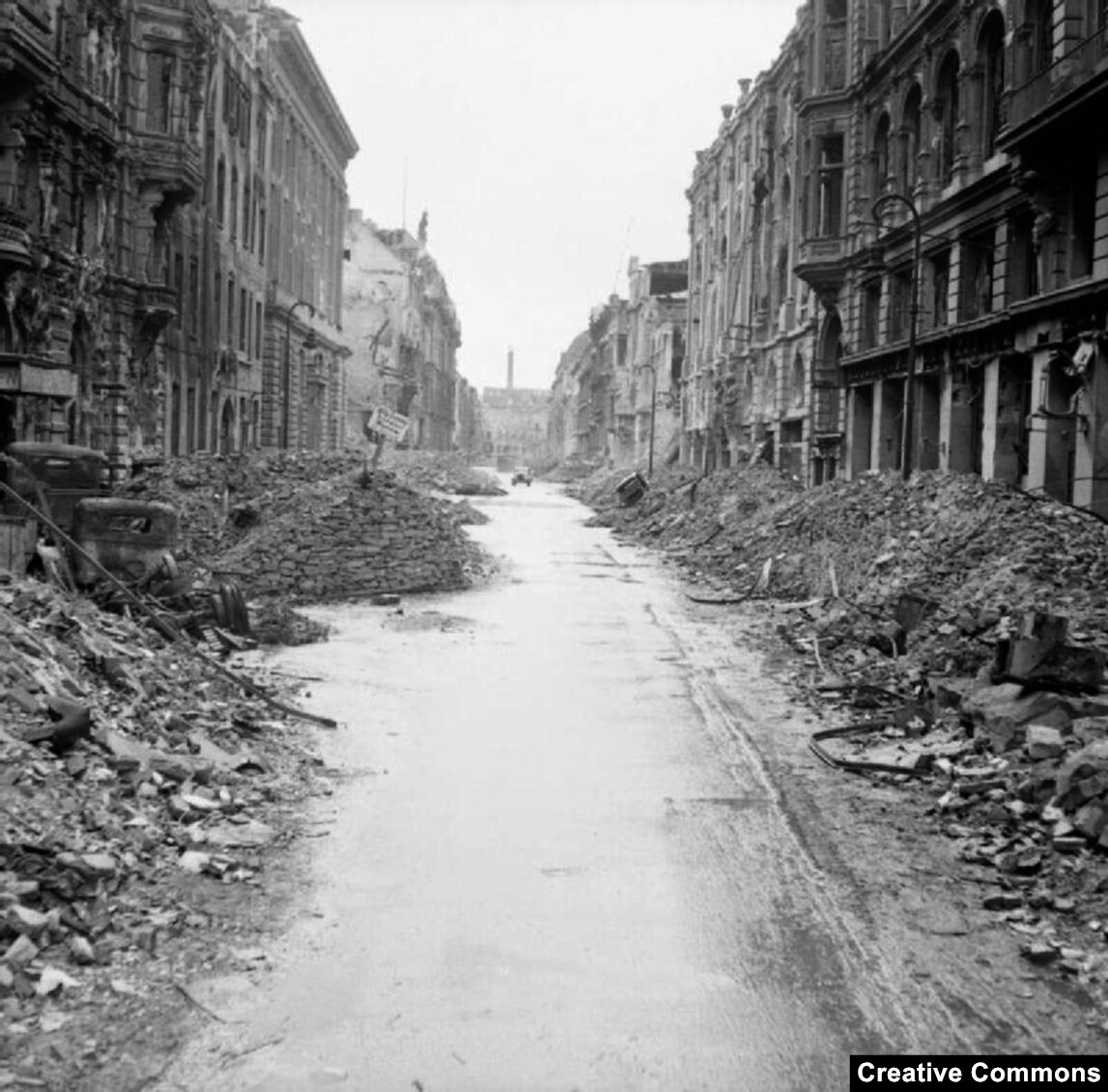一輛汽車沿著破敗的柏林街道行駛。  大部分損失是由英國、美國和法國的轟炸攻擊造成的，造成數萬名平民死亡。  