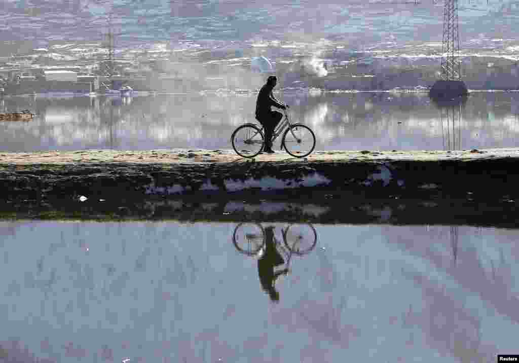 A man rides his bicycle across a lake in Kabul. (Reuters/Omar Sobhani)