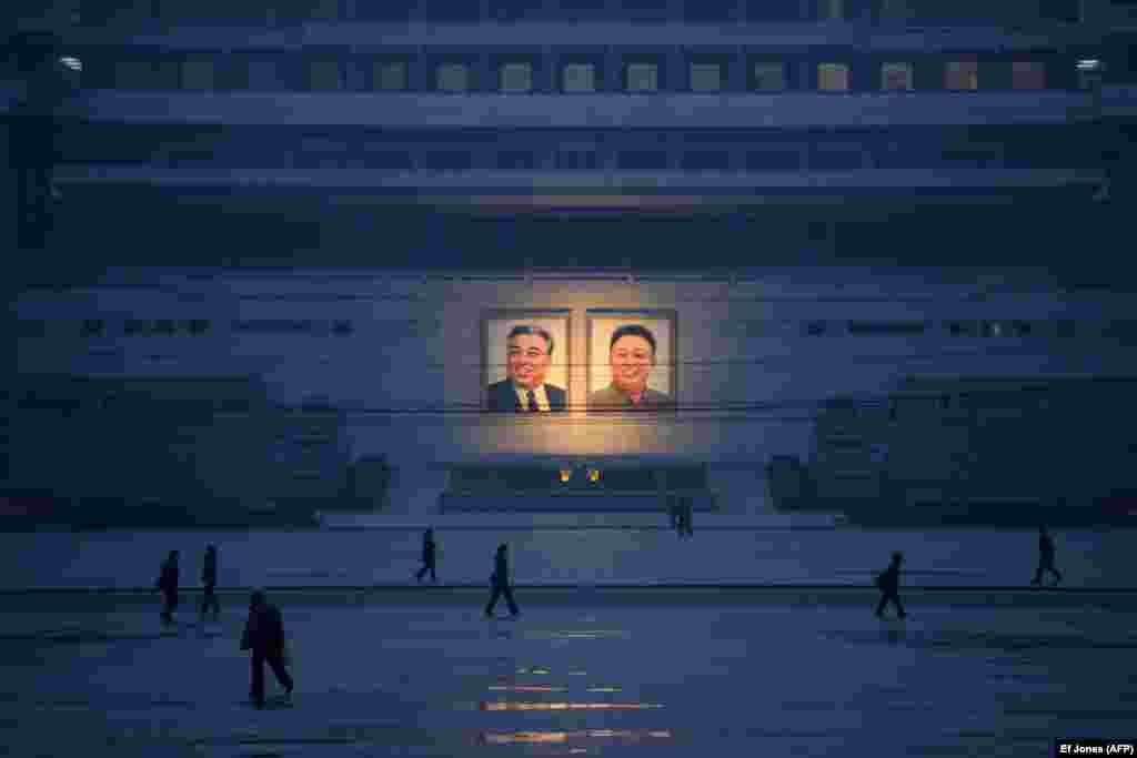Pedestrians walk past portraits of the late North Korean leaders Kim Il Sung and Kim Jong Il across Kim Il Sung Square in Pyongyang. (AFP/Ed Jones)