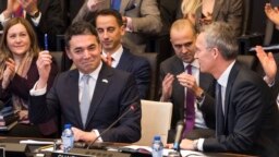 NATO Secretary-General Jens Stoltenberg (right) looks at Macedonian Foreign Minister Nikola Dimitrov as he holds a pen aloft during the signing of an "accession protocol" in a ceremony at NATO headquarters in Brussels on February 6. 