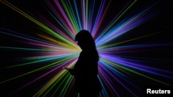 Science Museum employee Kerry Law poses for a photograph by an audiovisual display at the Large Hadron Collider exhibition at the Science Museum in London.