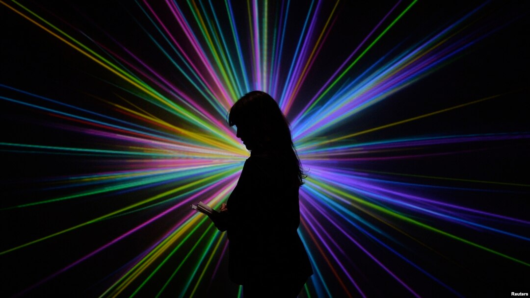 Science Museum employee Kerry Law poses for a photograph by an audiovisual display at the Large Hadron Collider exhibition at the Science Museum in London.