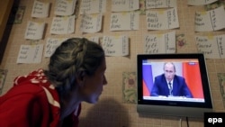 A woman watches a news program showing Russian President Vladimir Putin making a statement about the Syria situation in St. Petersburg on September 30.