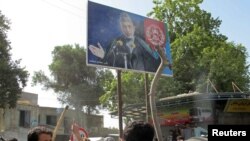 Afghanistan -- People hrow rocks at a picture of President Hamid Karzai during a protest in Taloqan, 18May2011